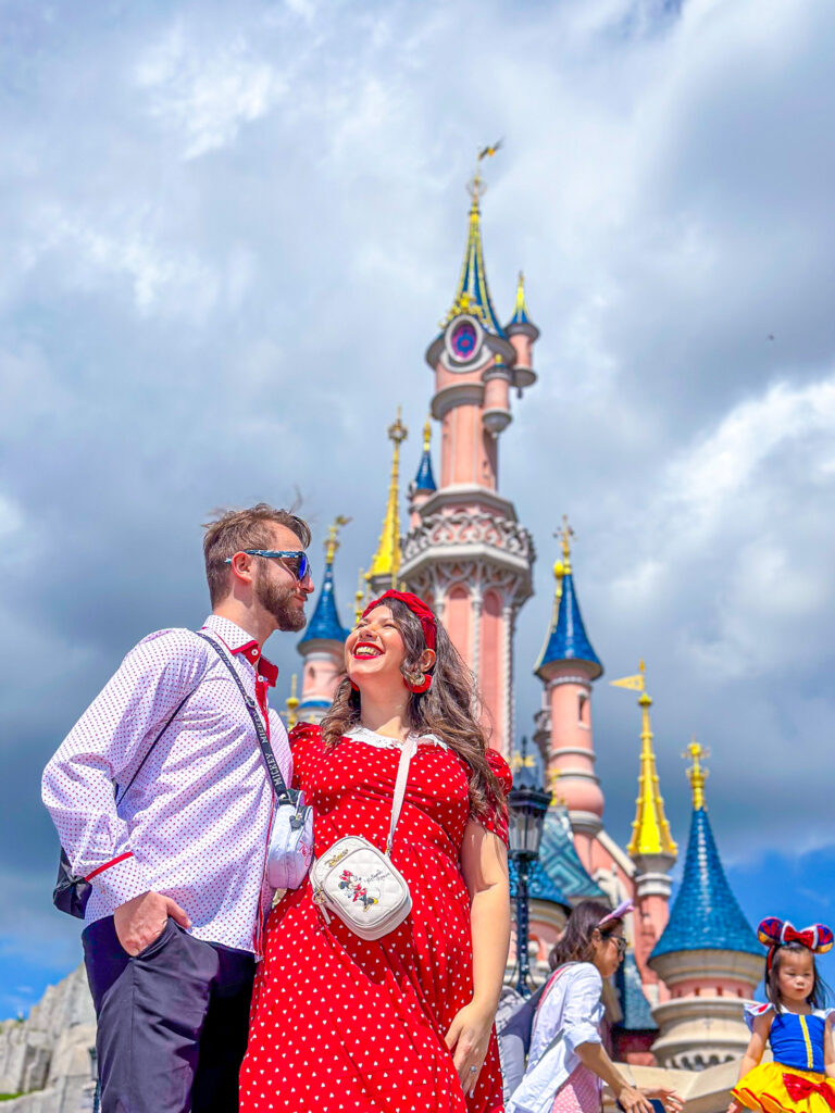 Due ragazzi che sorridono davanti al castello magico di Disneyland Paris mentre sono in viaggio di lavoro e guadagnano viaggiando